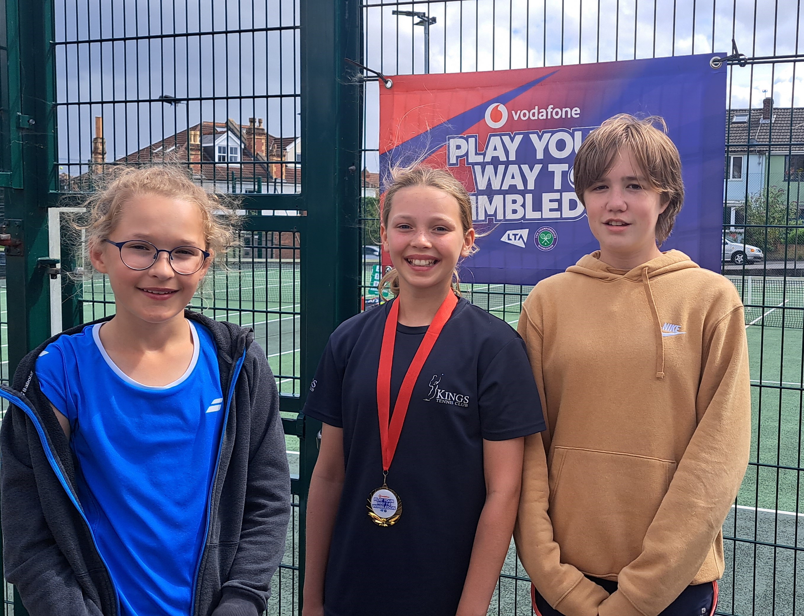 Winners of girls tennis tournament in front of a tennis court  